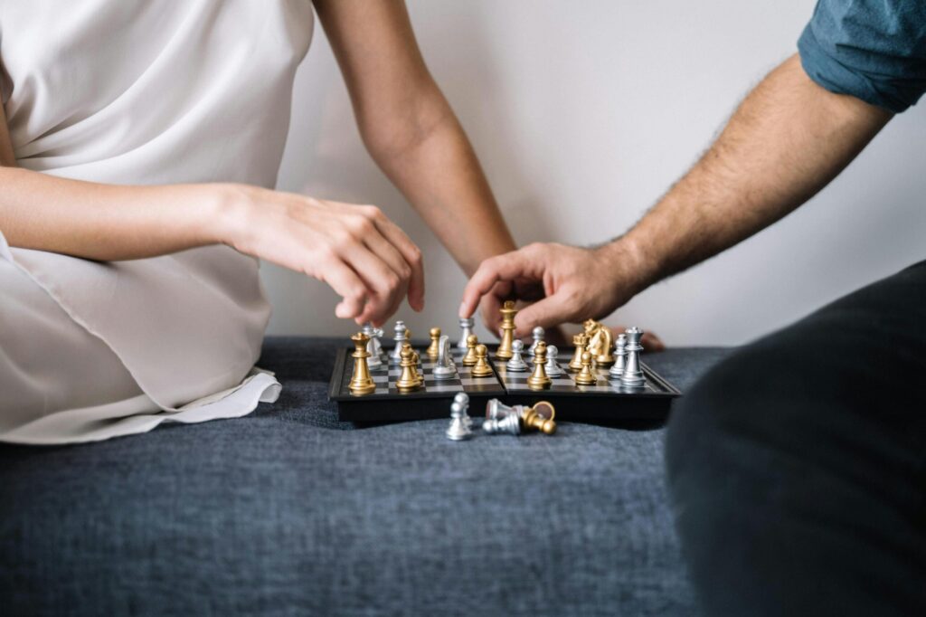 Close-up of two adults engaged in a strategic chess game indoors.